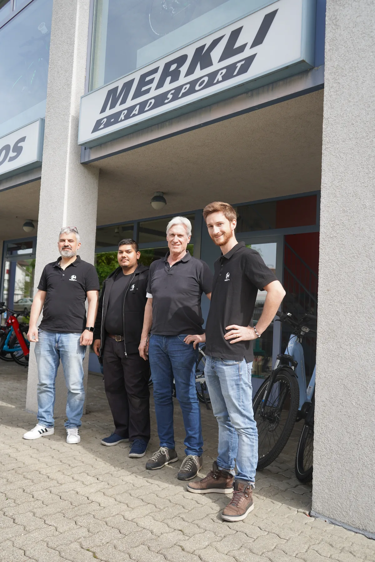 Gruppenbild mit vier Männern vor dem Eingang zu Merkli 2-Rad Sport in Wetzikon.