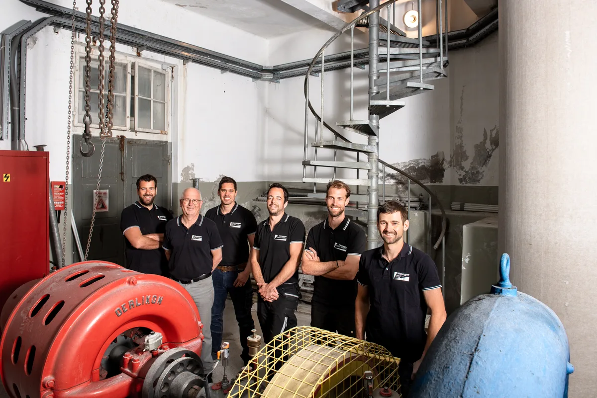 Walter Honegger (Zweiter von links) im Kreis seiner Mitarbeiter, die zu Aktionären wurden (von links): Simon Honegger, Dominik Honegger, Remo Blöchlinger, Andrin Vontobel und Lukas Stettler. Sechs Männer stehen hinter einer grossen roten Turbine.