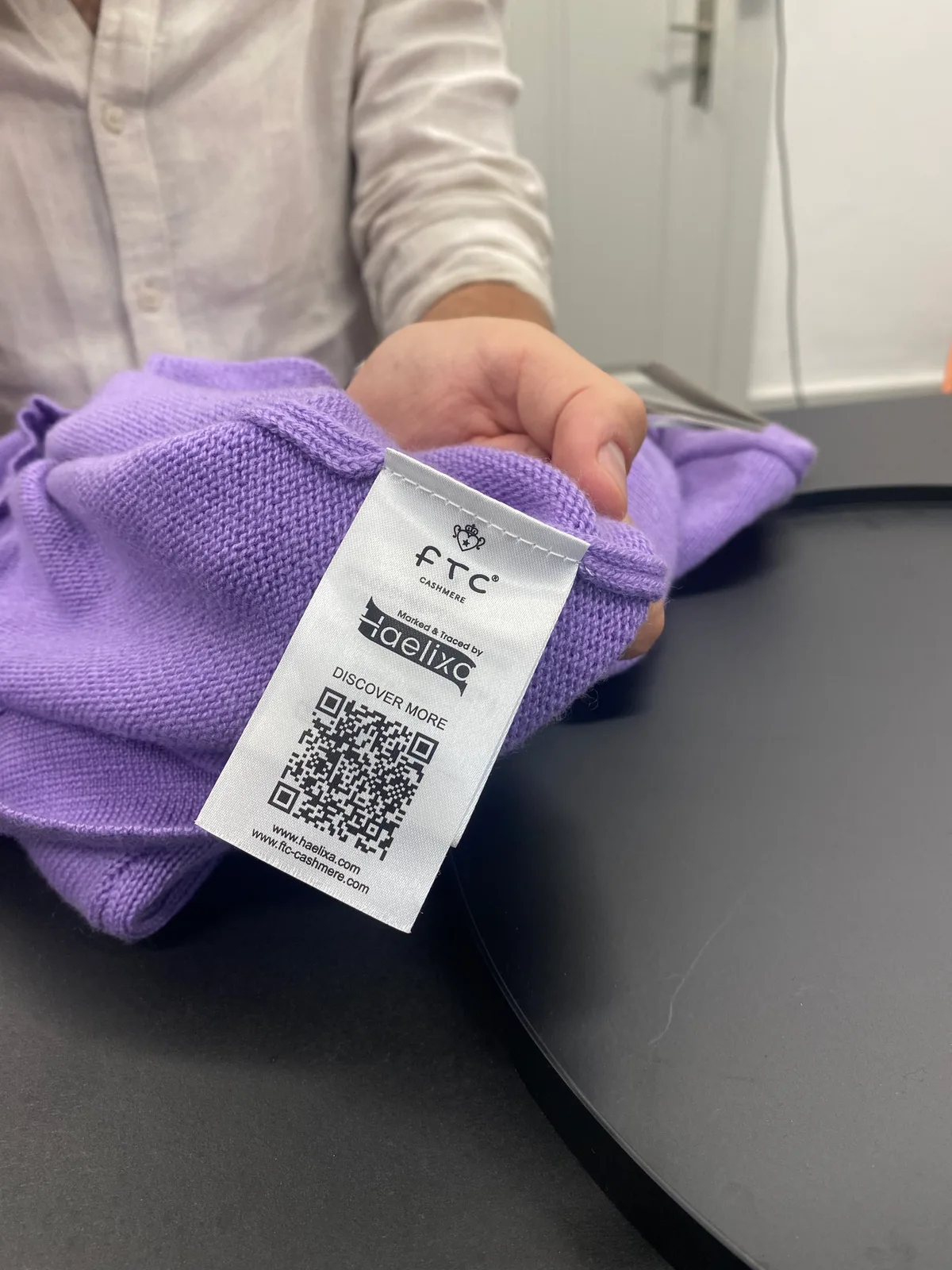 Die Etikette in einem violetten Kaschmirpullover zeigt das Logo des Modelabels FTC und von Haelixa.