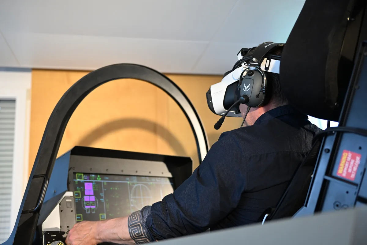 Ein Mann sitzt mit VR-Brille im Cockpit eines Flugsimulators.