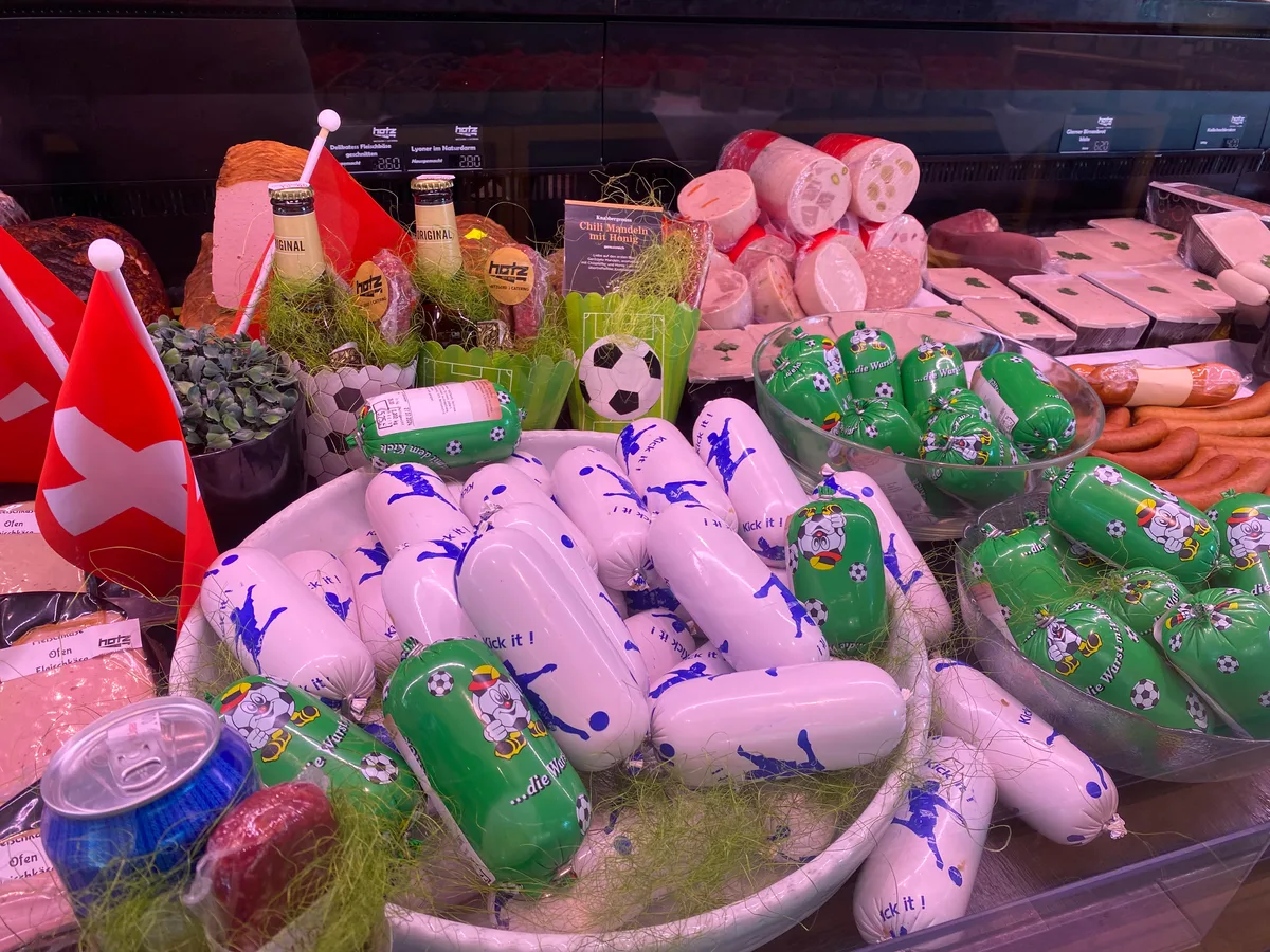 Die Kühltheke der Metzgerei Hotz. Man sieht verschiedene Produkte, die mit Fussballsujets geschmückt sind.