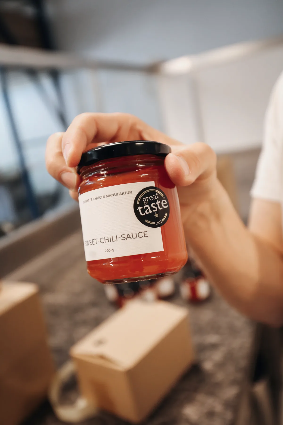 Eine Hand hält ein Glas mit der Aufschrift «Sweet-Chili-Sauce».