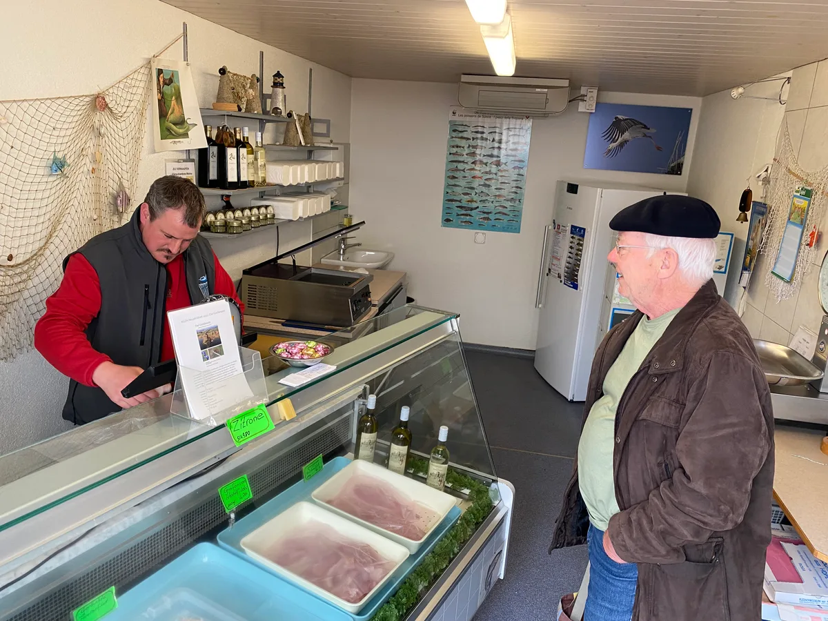 Noch verkauft Andreas Zollinger in seinem Laden in Riedikon Fische. Ab Ende April dann die Einrichtung. Ein älterer Mann steht vor einer Kühltheke mit Fischen. Dahinter der Fischer.