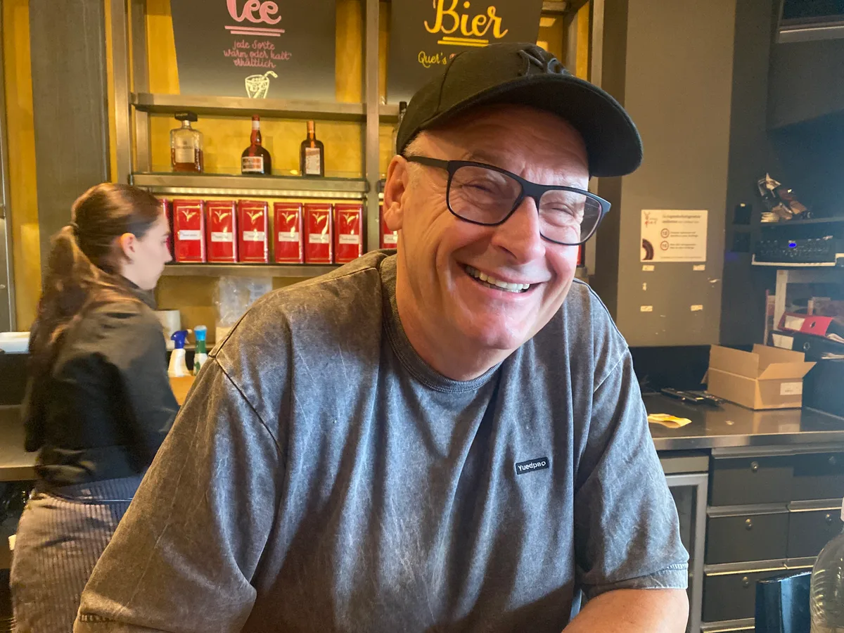 Ein Mann mit Brille und Baseballmütze lächelt in die Kamera.