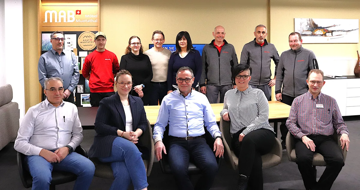 Gruppenbild des Team des Einrichtungshauses Möbel Waeber in Pfäffikon. 13 Menschen, fünf sitzen auf einem Sofa, acht stehen dahinter.