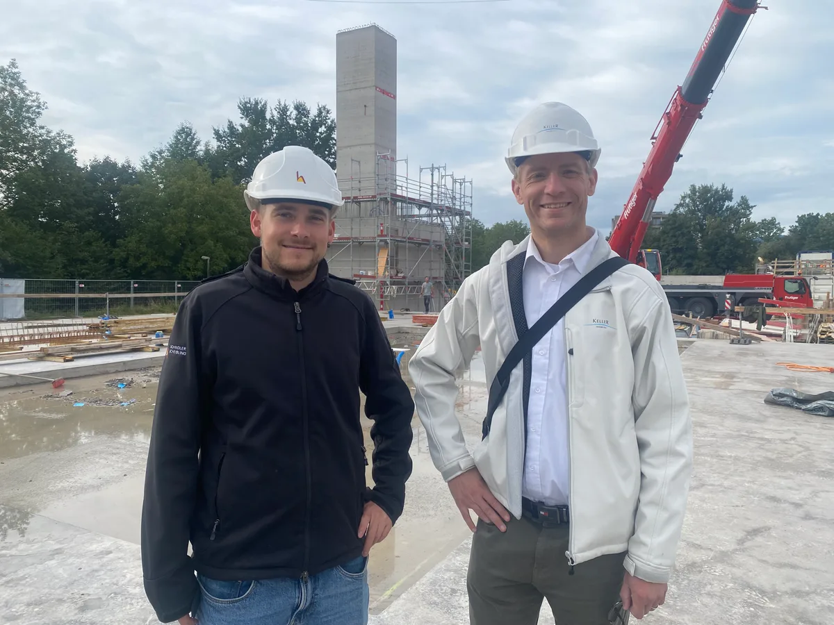 Zwei Männer mit Bauhelmen stehen auf einer Betonplatte.