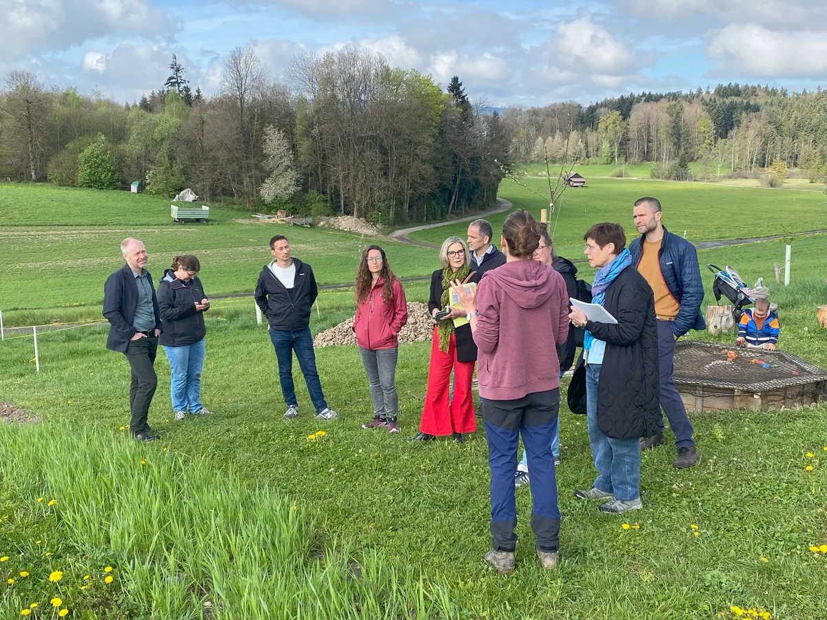 Judith Frei führt über ihren Hof Rinderbrunnen und erklärt die Philosophie des Betriebs. Eine Gruppe Menschen stehen auf einer Wiese. Von hinten sieht man Bäuerin Judith Frei, die den Rundgang über ihren Betrieb führt.