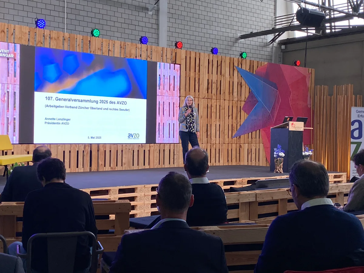 AVZO-Präsidentin Annette Lenzlinger steht auf einer Bühne aus Holzpaletten im Event Hangar des Innovationsparks Dübendorf.
