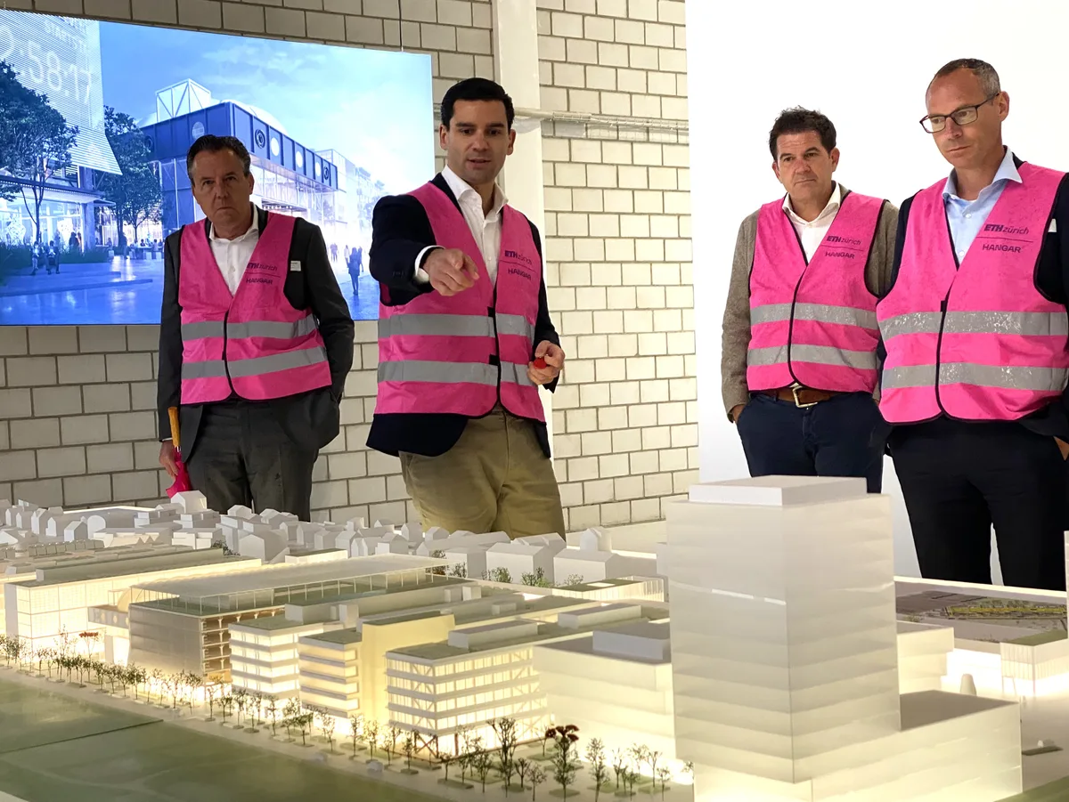 Männer in pinken Warnwesten stehen um das Modell des Innovationsparks Dübendorf.