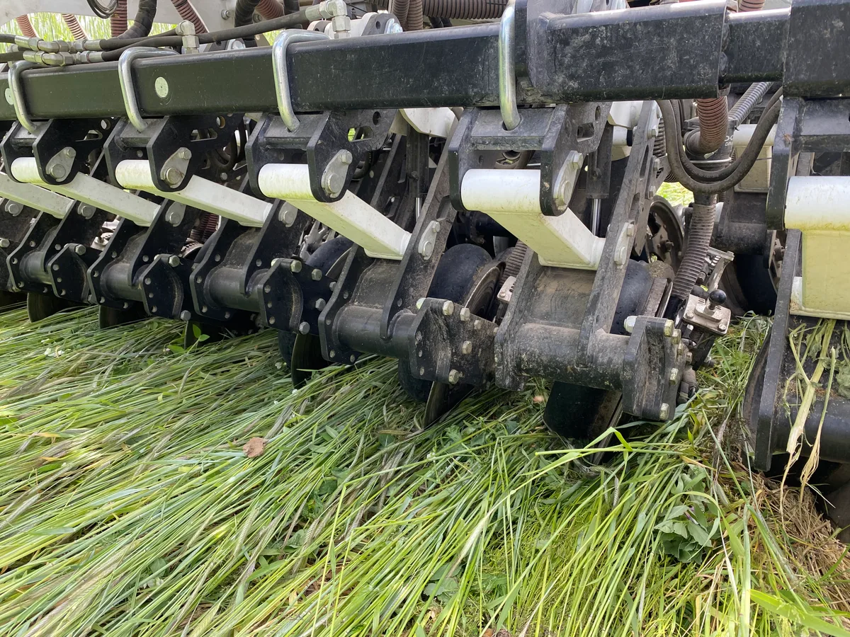 Dieser wird mit der Direktsaat-Maschine gesät, ohne dass der Boden gepflügt wird. Detailaufnahme einer Direktsaat-Maschine. Man sieht eine Reihe von Metallscheiben, mit denen feine Furchen in den Boden gezogen werden.