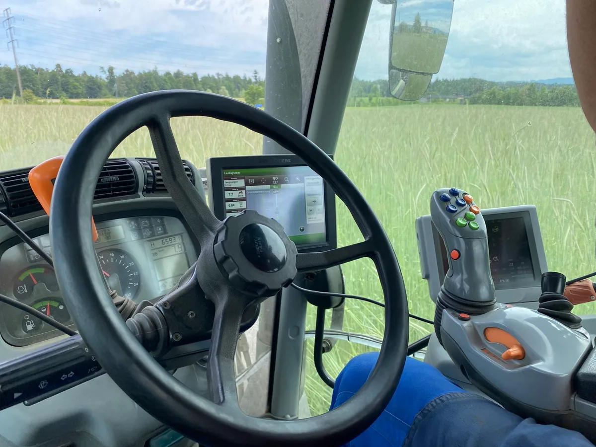Während der Fahrt auf seinem Buchweizenfeld kann der Landwirt die Hände vom Steuer nehmen. Das Lenkrad eines Traktors. Dahinter ein Bildschirm, der die GPS-Ortung zeigt.