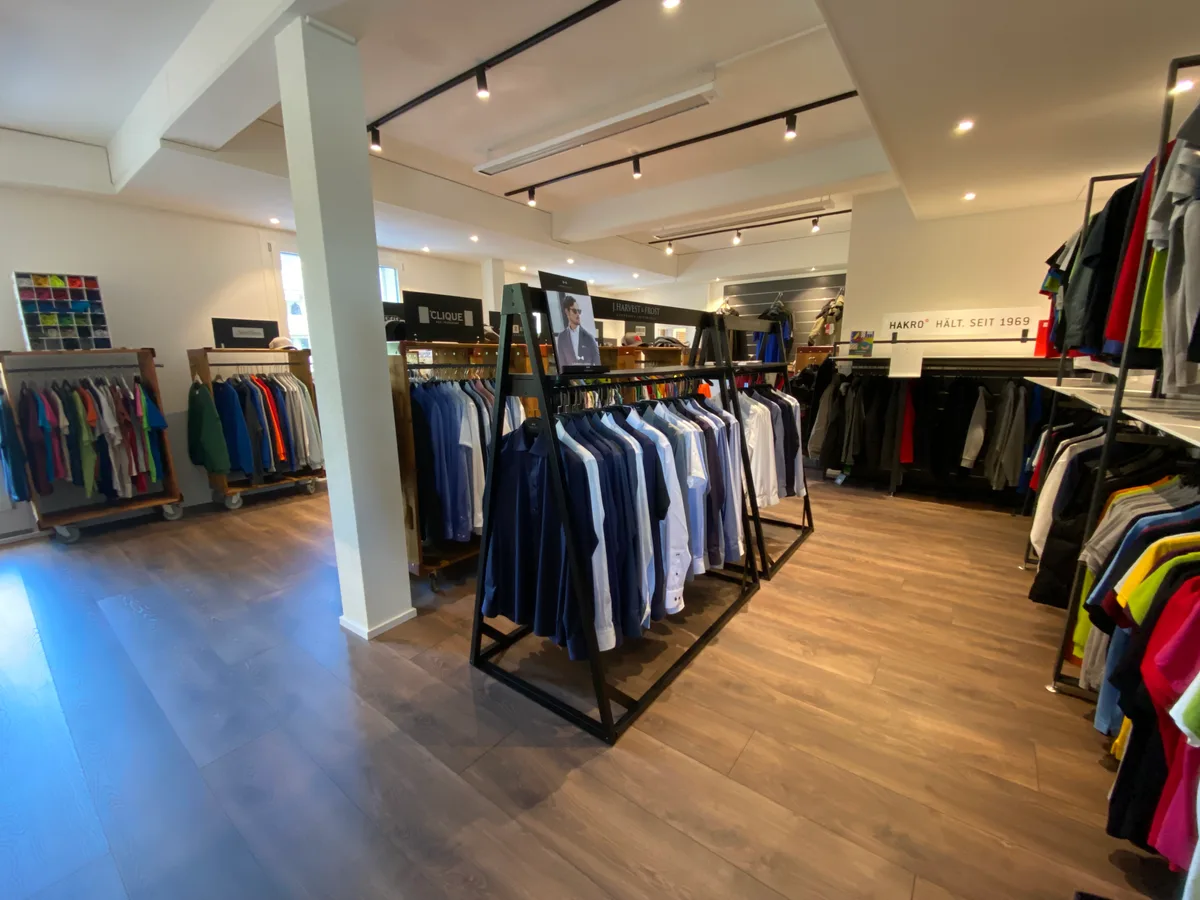 Blick in den Showroom der Newoutfit AG in Tann. Man sieht Gestelle mit Hemden, Shirts und Baseballcaps in verschiedenen Farben.