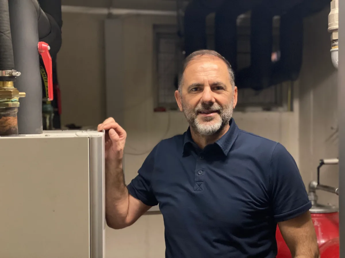 Porträt von Arben Selmonaj: Er trägt ein dunkelblaues Polo und einen grauen Bart.