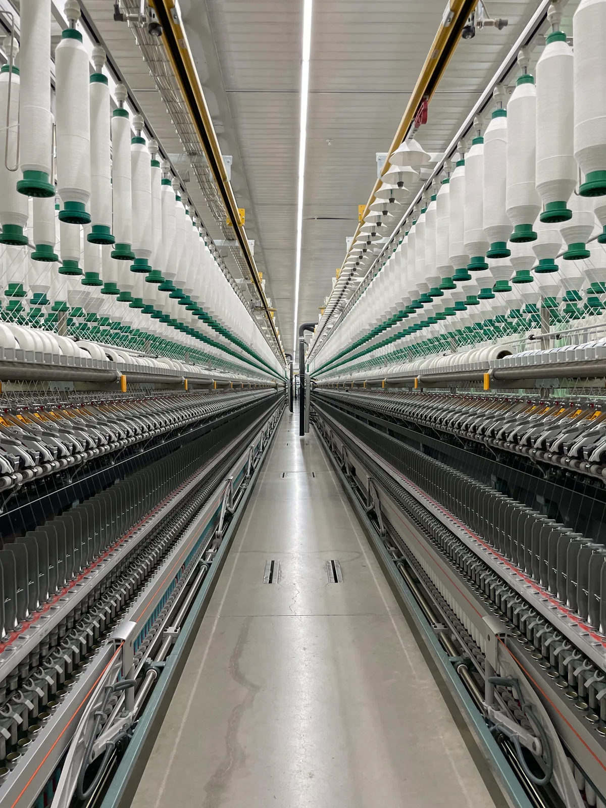 Spinnmaschinen von Rieter im Werk von Säntis Textiles in der Südtürkei. Produktion von Recycling-Baumwolle im Säntis-Werk in der Südtürkei. Man sieht Spindeln, auf die das Garn gewickelt wird.