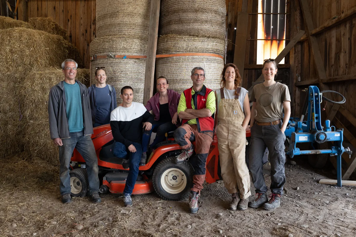 Das Team des Hofs Rinderbrunnen in Grüt. Ein Gruppenbild des Kollektivs des Hofs Rinderbrunnen. Vier Frauen und drei Männer posieren in einer Scheune auf und um einen Rasenmäher.