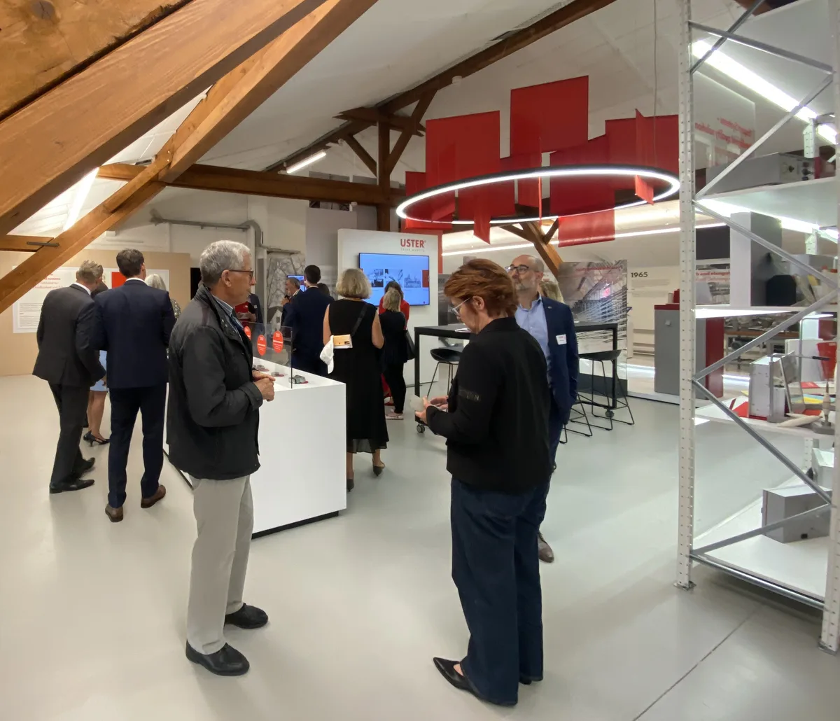 Blick ins Museum von Uster Technologies. Man sieht Regale mit Exponaten und in der Mitte des Raums eine kreisförmige Leuchte über einem Tisch.