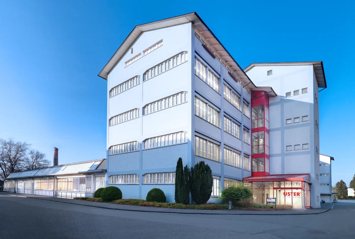 Der Sitz von Uster Technologies in Uster. Ein hellblaues, fünfgeschossiges Gebäude mit Satteldach.