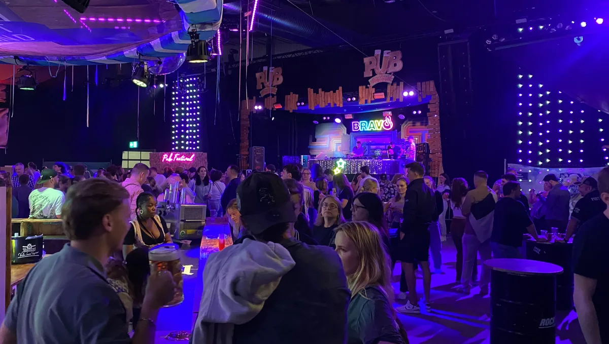 Feiernde Menschen am Pub-Festival in Wetzikon. Die Eishalle ist dekoriert und in buntes Licht getaucht.