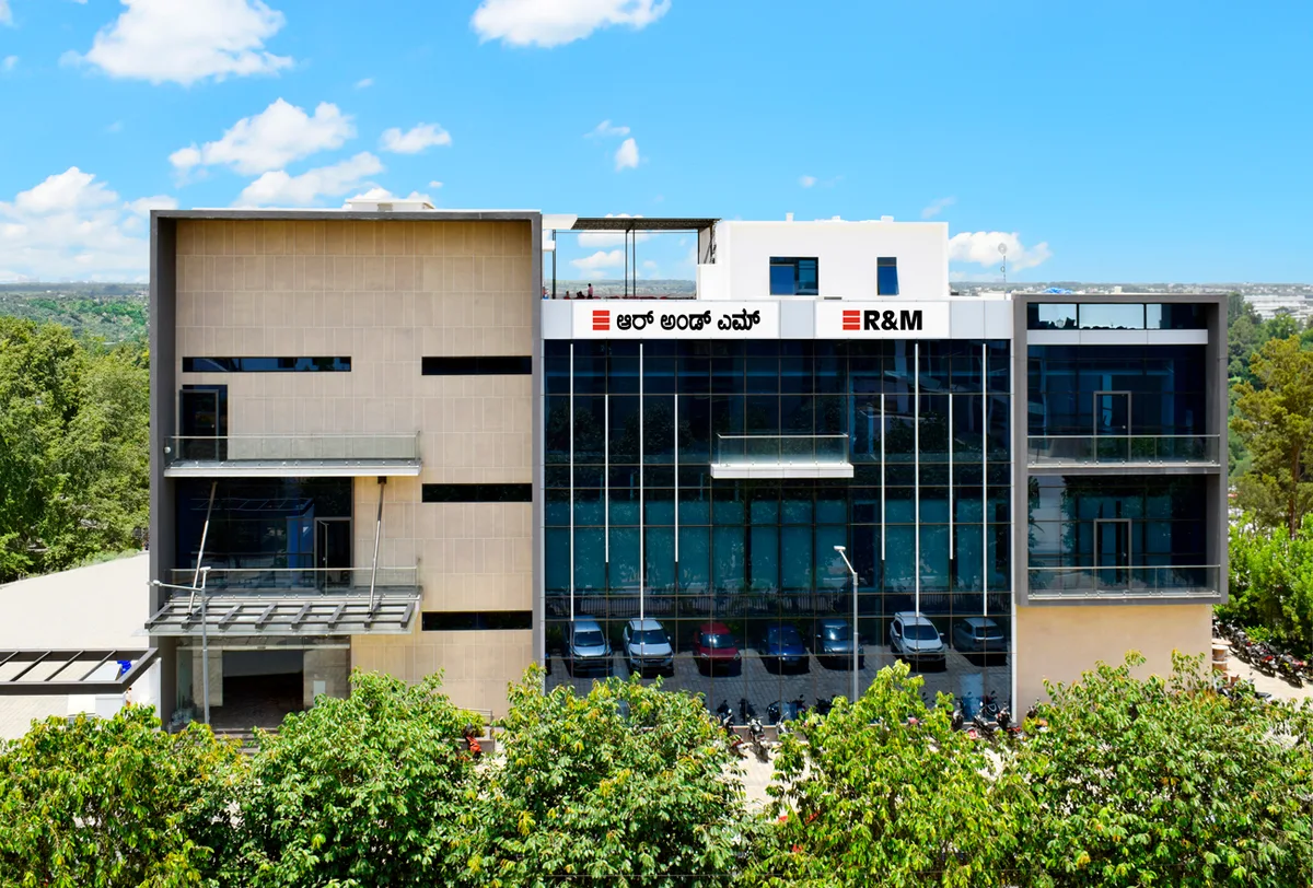 Das Produktionswerk für Fiberoptik in Indien wurde im Mai 2024 eröffnet: R&M beschäftigt in Bangalore mittlerweile 430 Mitarbeitende. (Archiv) Ein dreistöckiges Fabrikgebäude von aussen. Im Vordergrund grün belaubte Bäume.