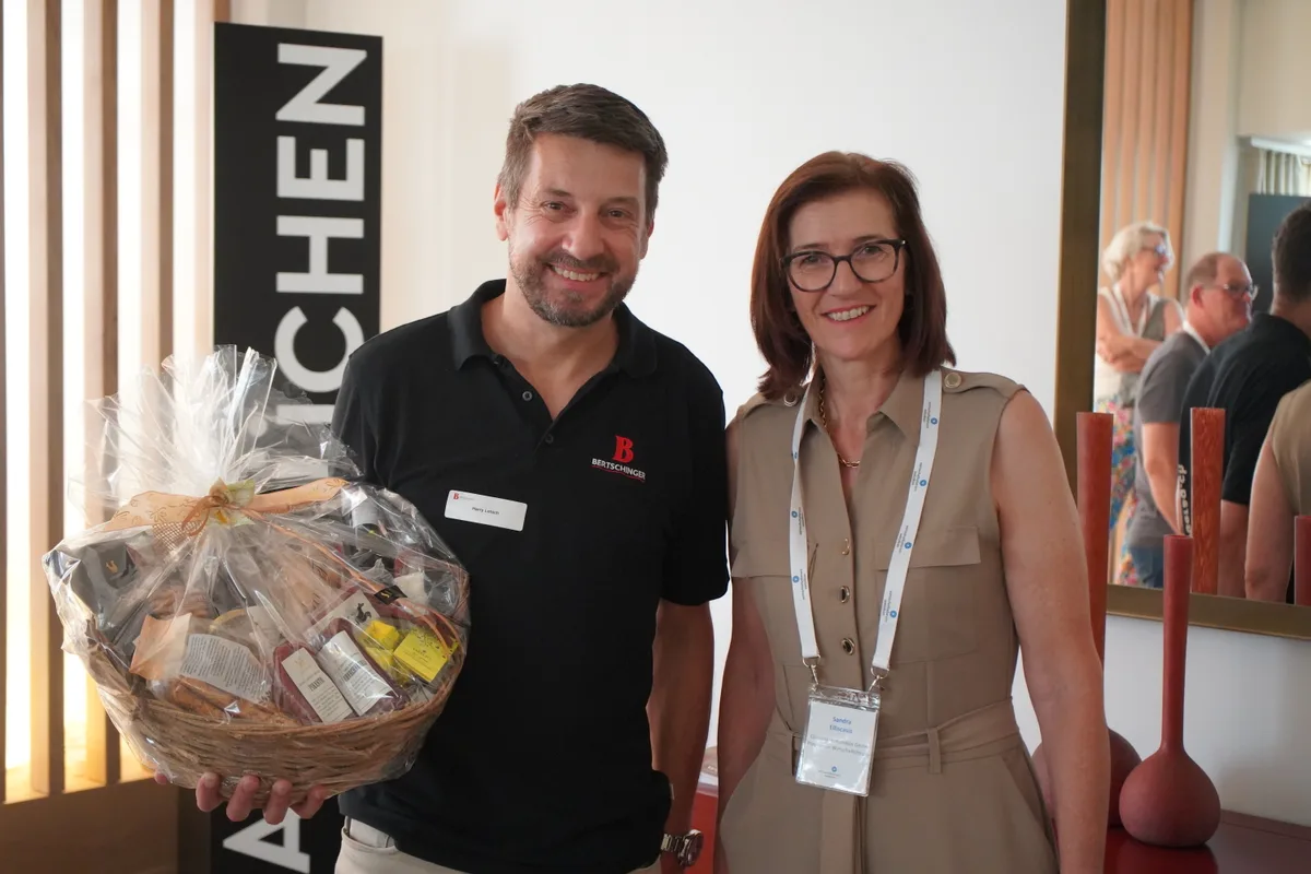 Harry Letsch und Sandra Elliscasis lächeln in die Kamera. Er hält einen Früchtekorb in seiner linken Hand.