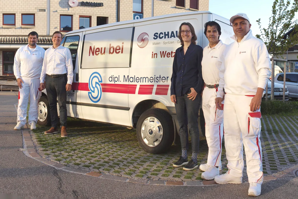 Eine Frau und vier Männer stehen vor einem weissen Lieferwagen.