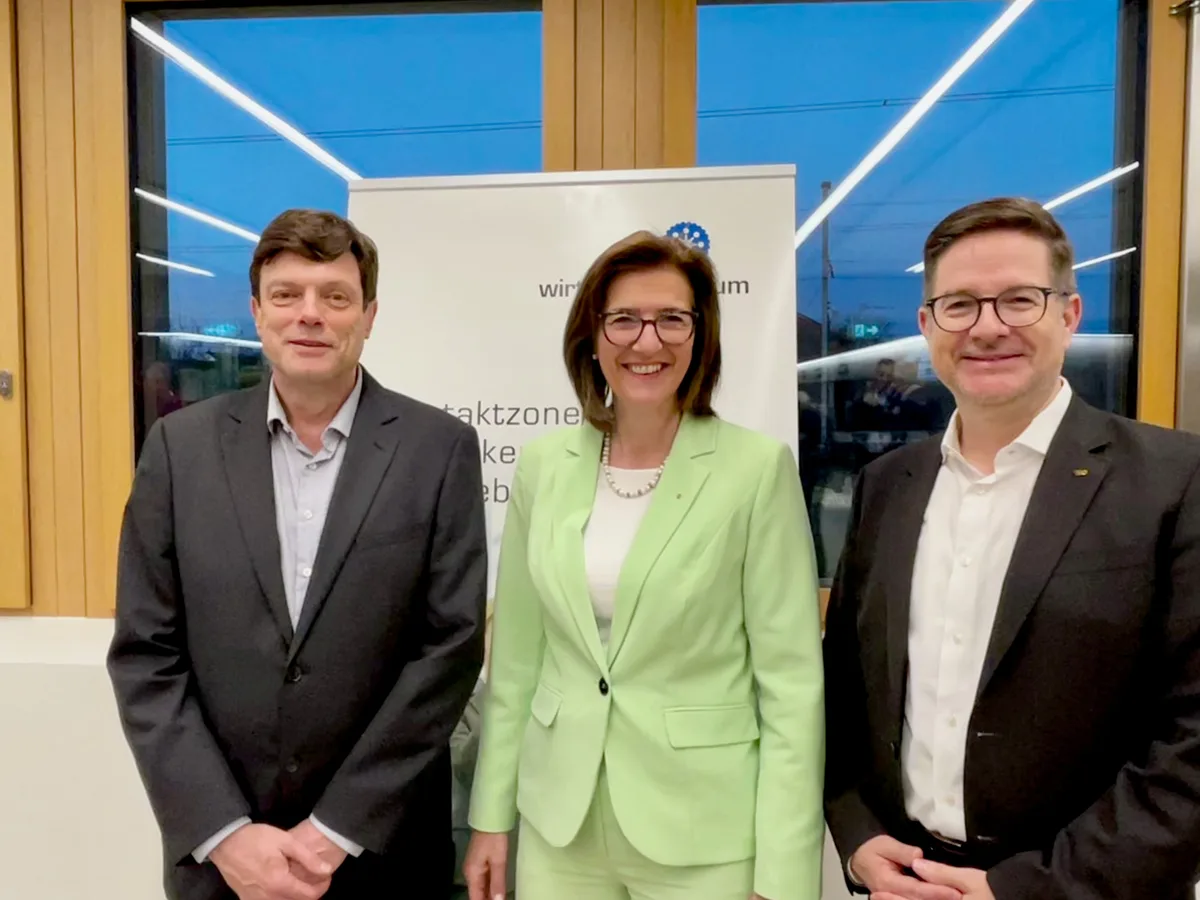 Gruppenbild mit zwei Männern und einer Frau in lindengrünem Anzug in der Mitte.