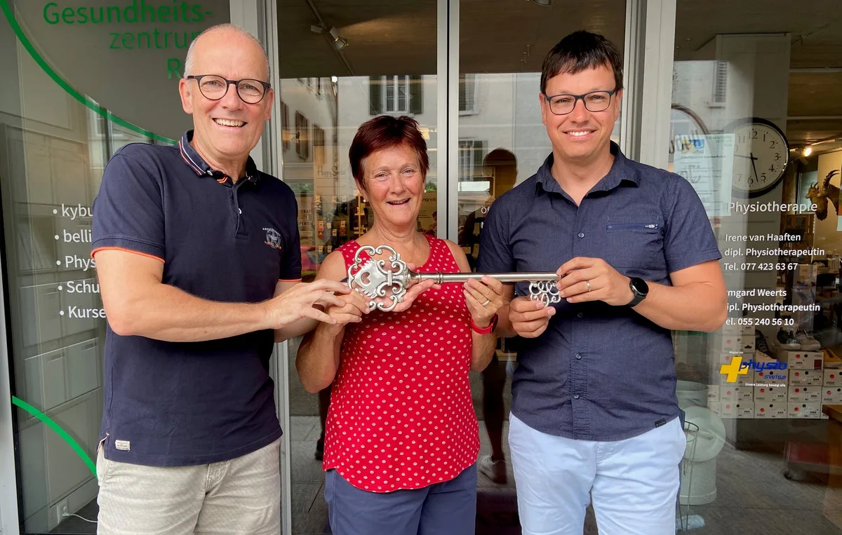 Zwei Männer und eine Frau halten einen grossen Schlüssel in der Hand.