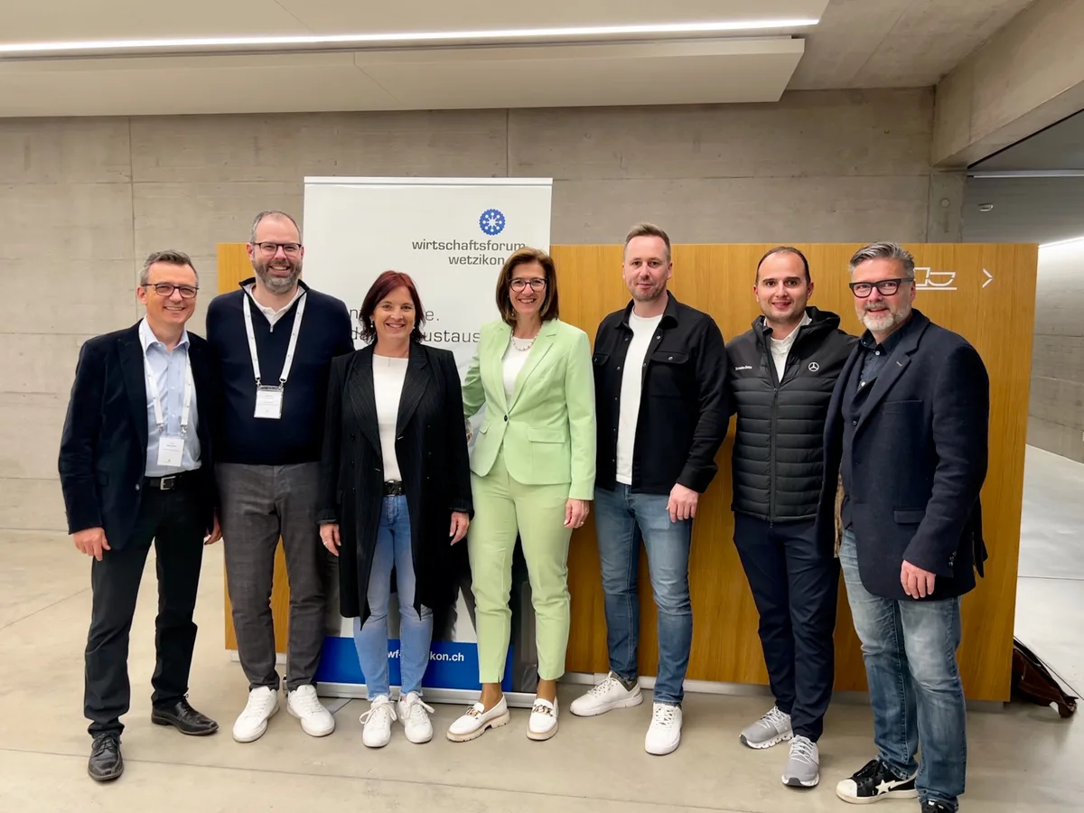 Der Vorstand des Wirtschaftsforums Wetzikon (von links): Revisor Jürg Wettstein, Ramon Strittmatter, Eliane Schumacher, Präsidentin Sandra Elliscasis, Mike Koller, Edi Oroshi und Sandro Compagno. Gruppenbild des Vorstands des Wirtschaftsforums Wetzikon: fünf Männer und zwei Frauen stehen vor einer Holzwand.
