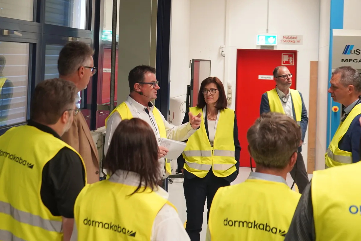 Menschen in gelben Warnwesten hören einem Mann zu.