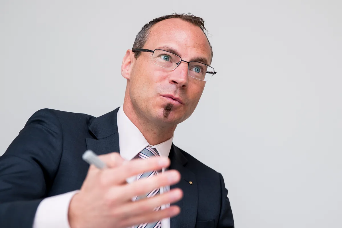 Ein Mann mit Kugelschreiber in der Hand erklärt etwas.