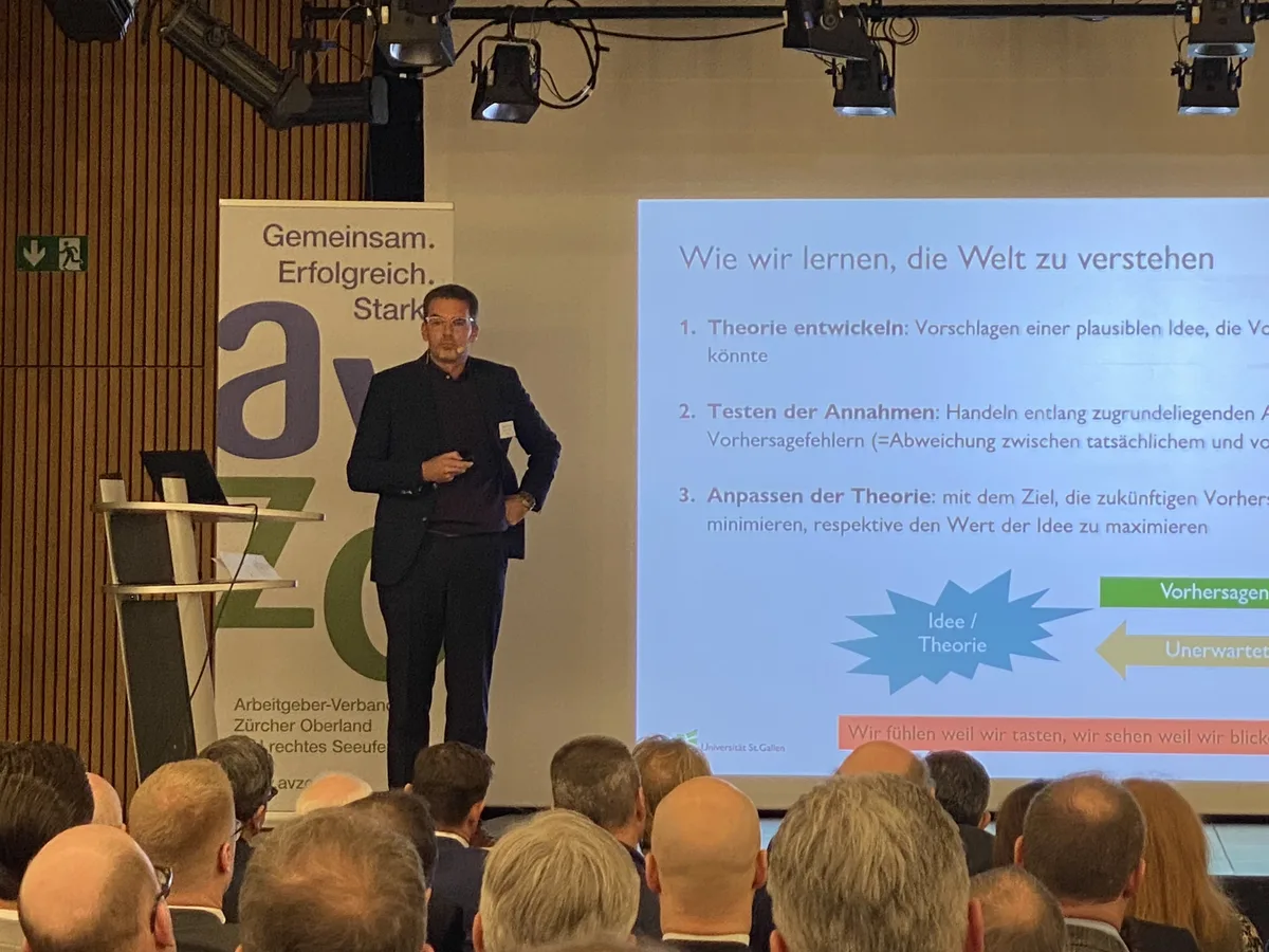 KMU und Familienunternehmen liegen im Fokus der Forschungsarbeit von Thomas Zellweger. Ein Mann im dunklen Anzug steht auf einer Bühne und referiert.