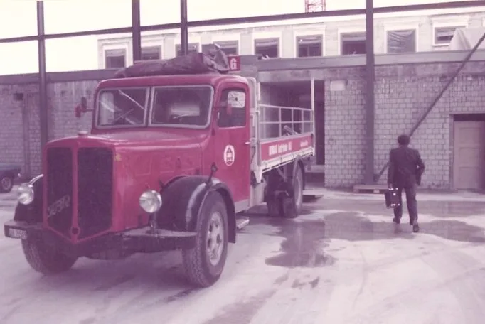 Ein roter LKW der Marke FBW steht in einer im Bau befindlichen Lagerhalle.