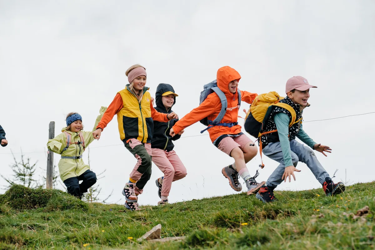 Die Namuk Holding AG aus Wetzikon hat sich einen Namen gemacht mit langlebigen, qualitativ hochwertigen Kinderkleidern. Eine Gruppe von Kindern rennt über eine Wiese.