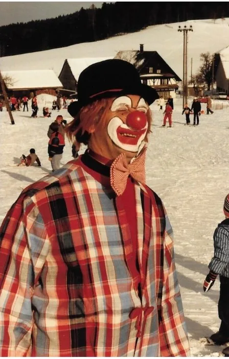 Ein Mann als Clown verkleidet auf einer Skipiste.