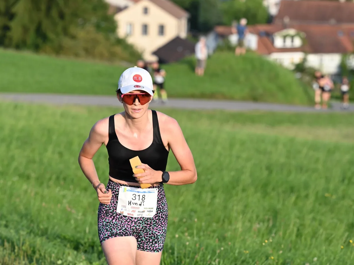 Eine Läuferin auf einer Bergstrasse, im Hintergrund Adetswil und weitere Läuferinnen