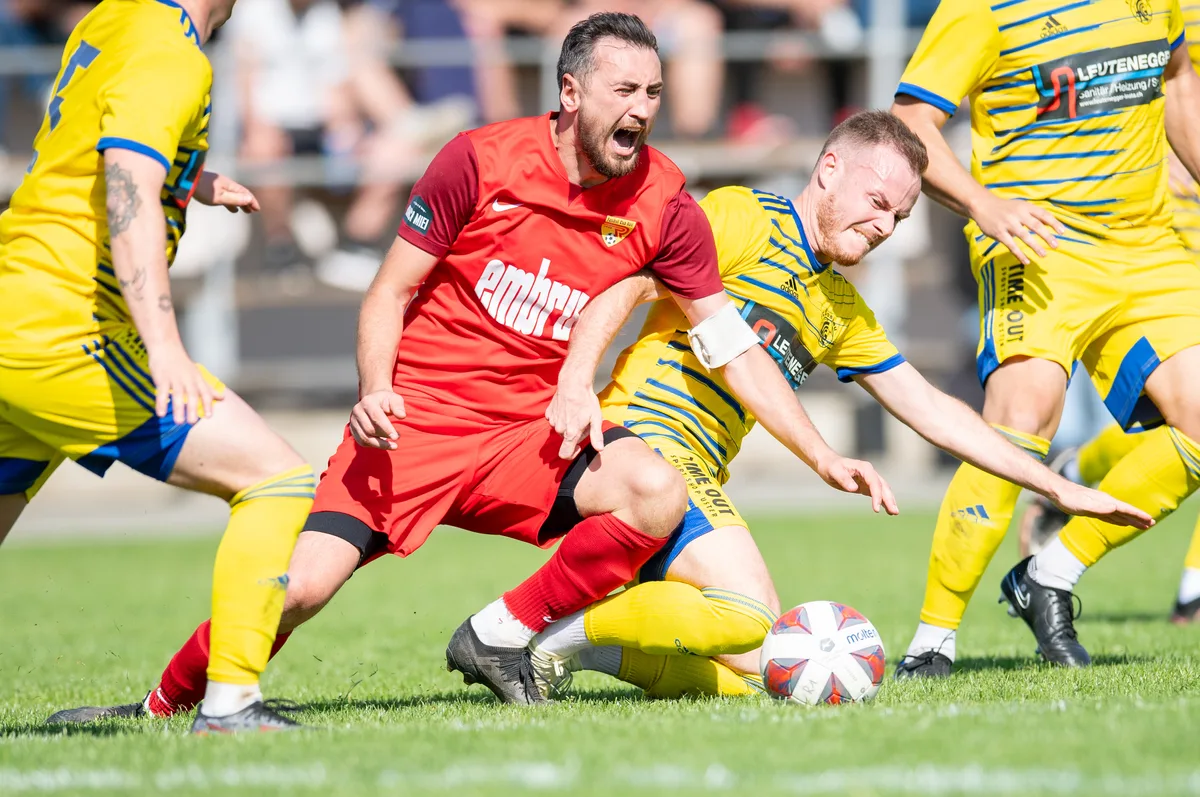 Fussballspieler grätschen auf einer Wiese.