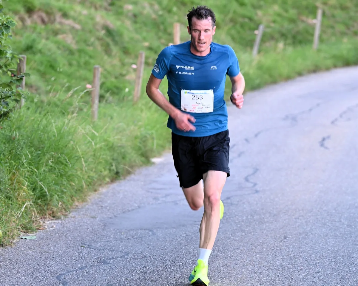 Ein Läufer in blauem T-Shirt auf einer Bergstrasse.