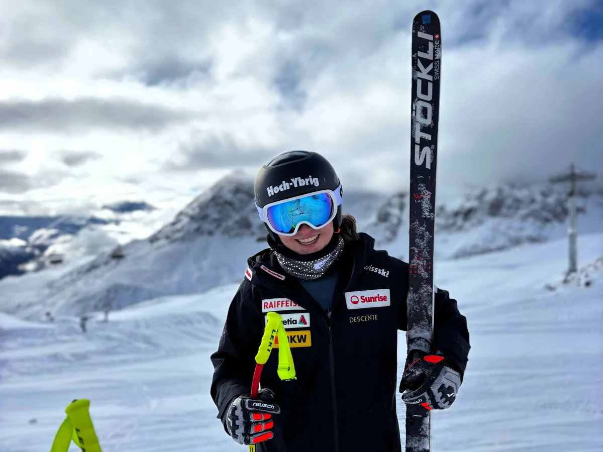 Eine Skirennfahrerin, die ihre Ski in den Armen hält.