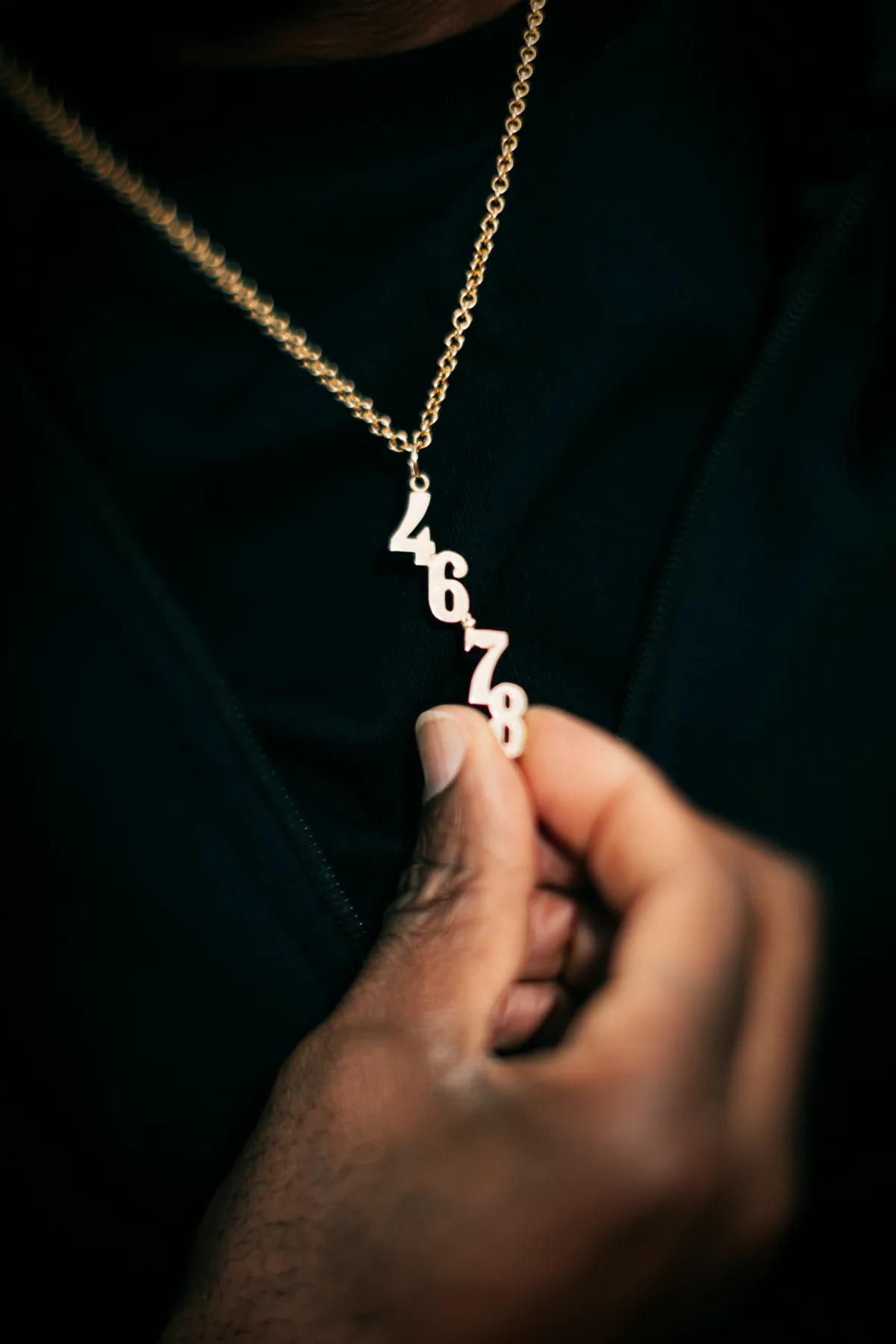 Eine Hand hält einen Kettenanhänger mit den Zahlen 4678.