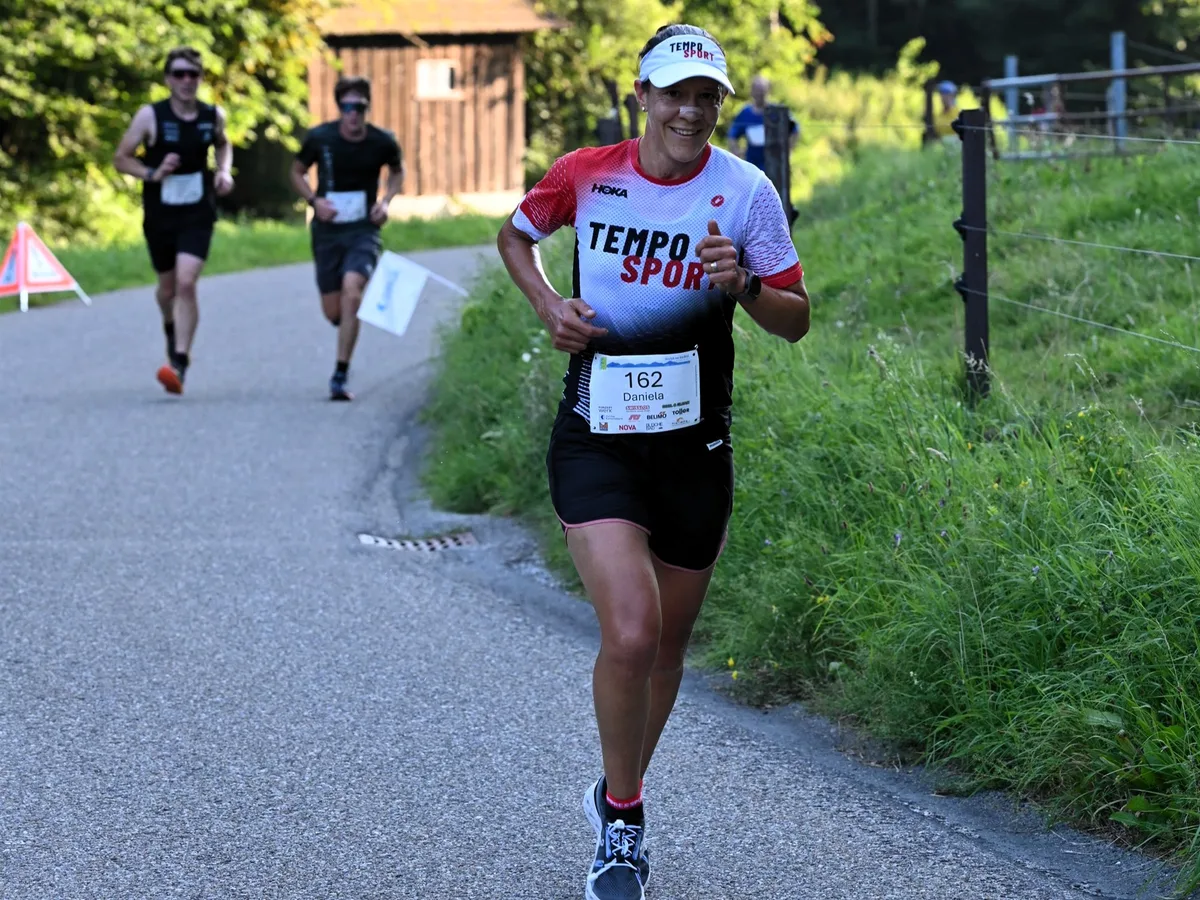 Eine Frau rennt auf einer Strasse, dahinter zwei Männer.