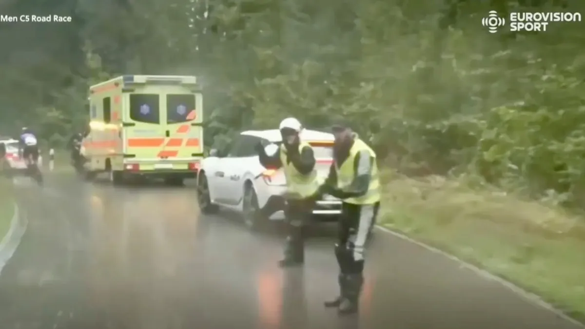 Eine Ambulanz und mehrere Streifenwagen stehen auf der Rennstrecke. Polizisten signalisieren, dass die Teilnehmer bremsen sollen. Rad-WM