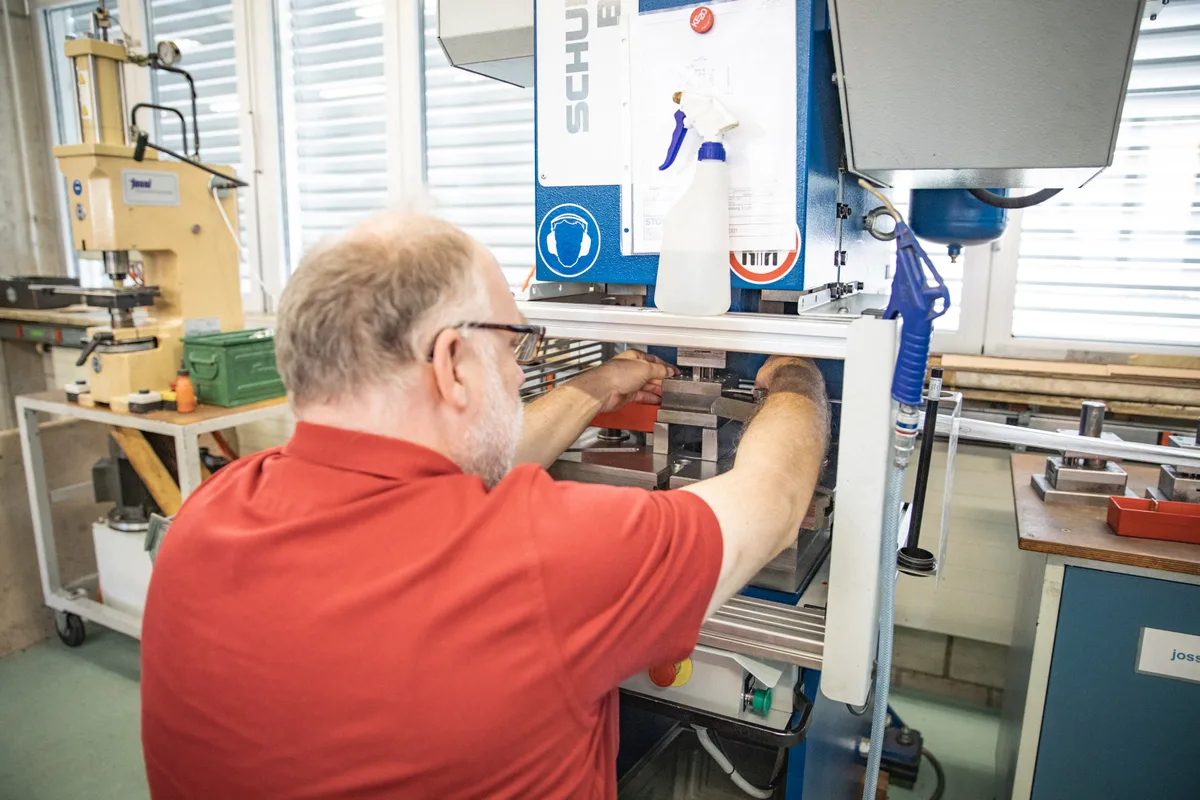 Bewohner des Gehörlosendorfs Turbenthal bei der Bedienung einer Stanzmaschine.