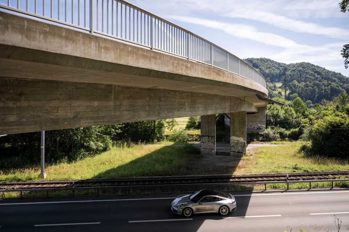 Ein Auto fährt unter einer Betonbrücke durch.