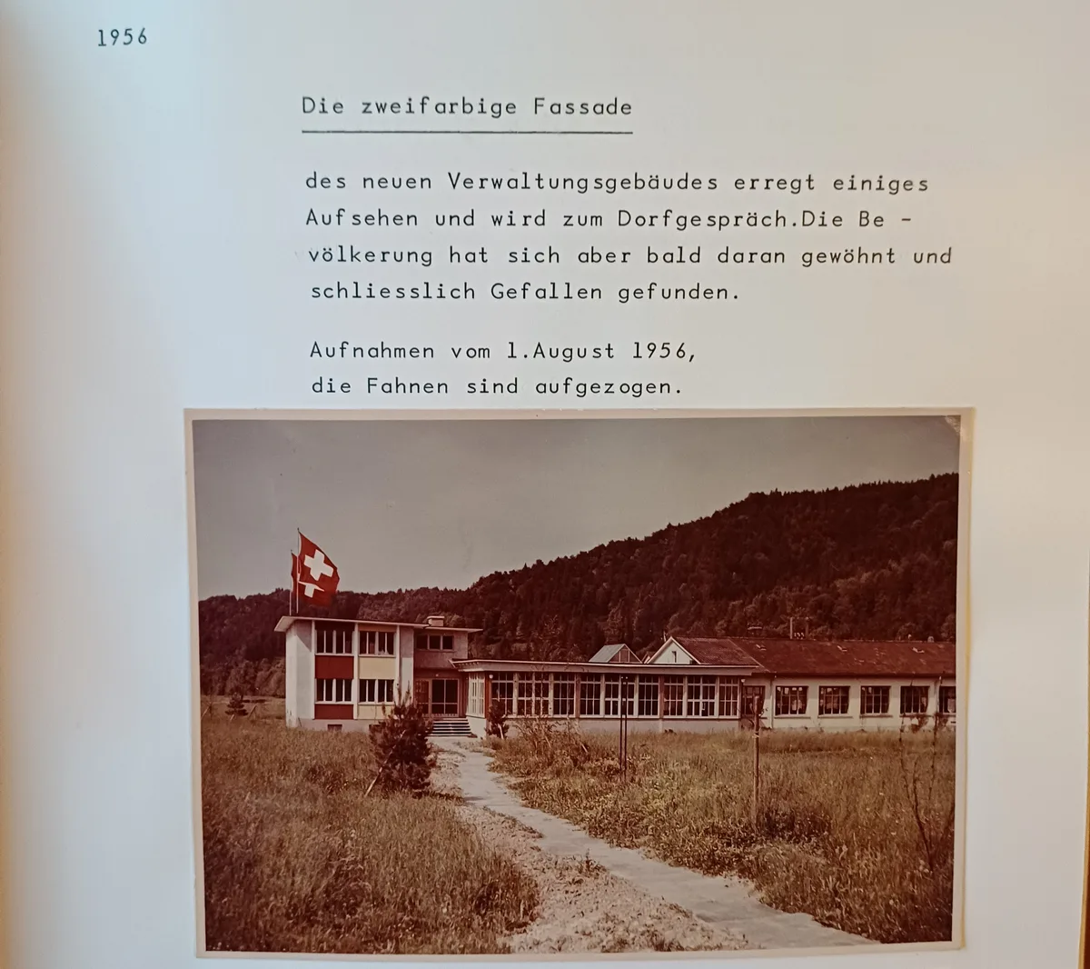Das Bild aus der Firmenchronik zeigt die Wabo, links zu sehen ist das Bürogebäude mit der zweifarbigen Fassade. gebäude mit fahnen