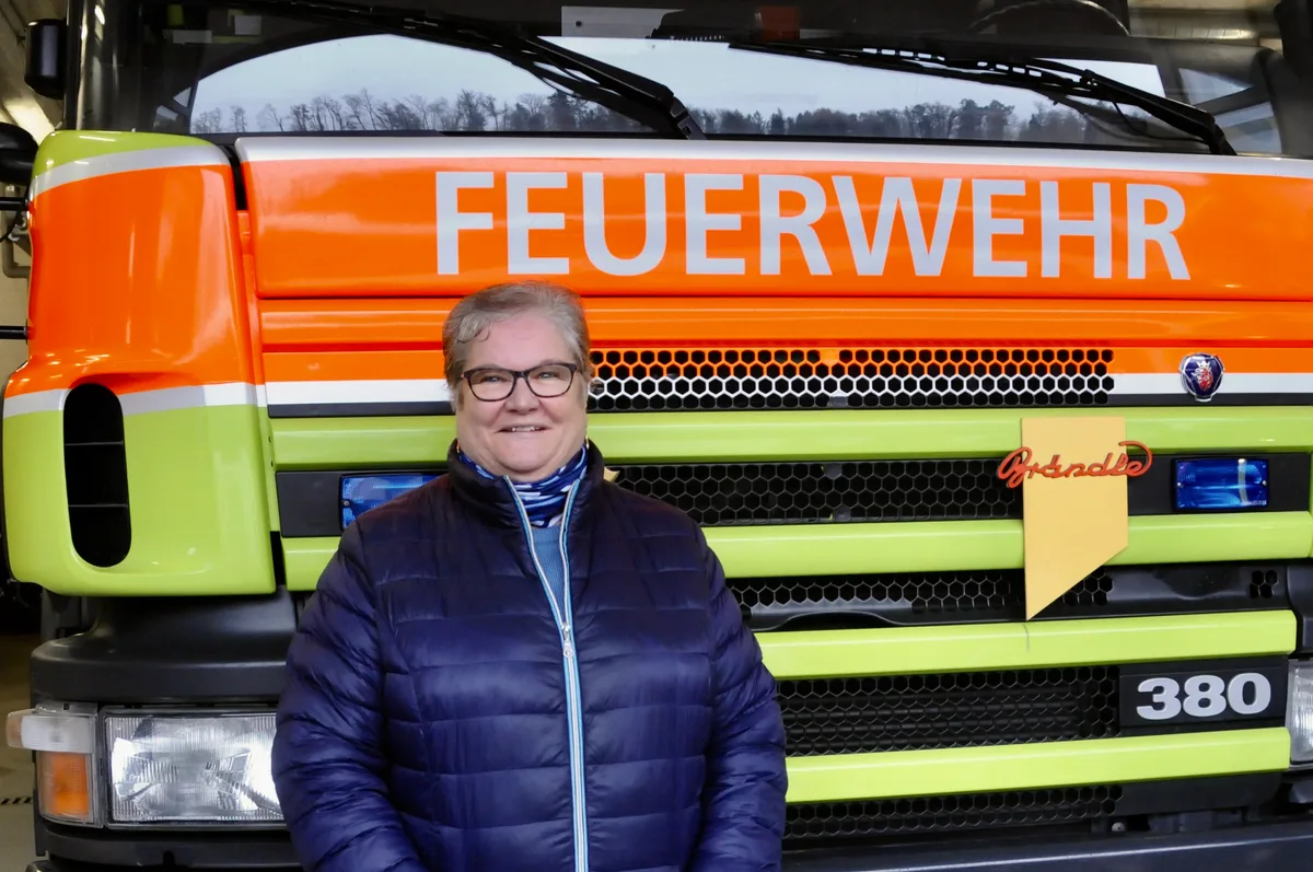 Man sieht eine Frau vor dem Feuerwehr-Einsatzfahrzeug.