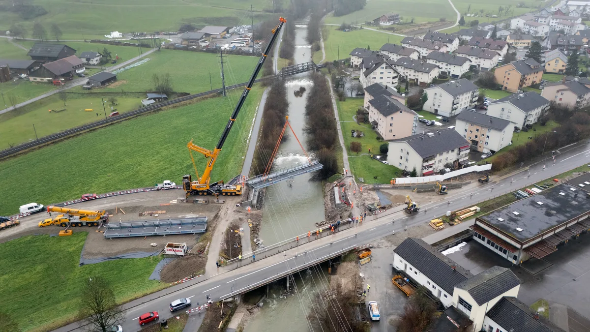 Blick auf die Töss in Wila. Ein Kran hebt eine Stahlbrücke an.