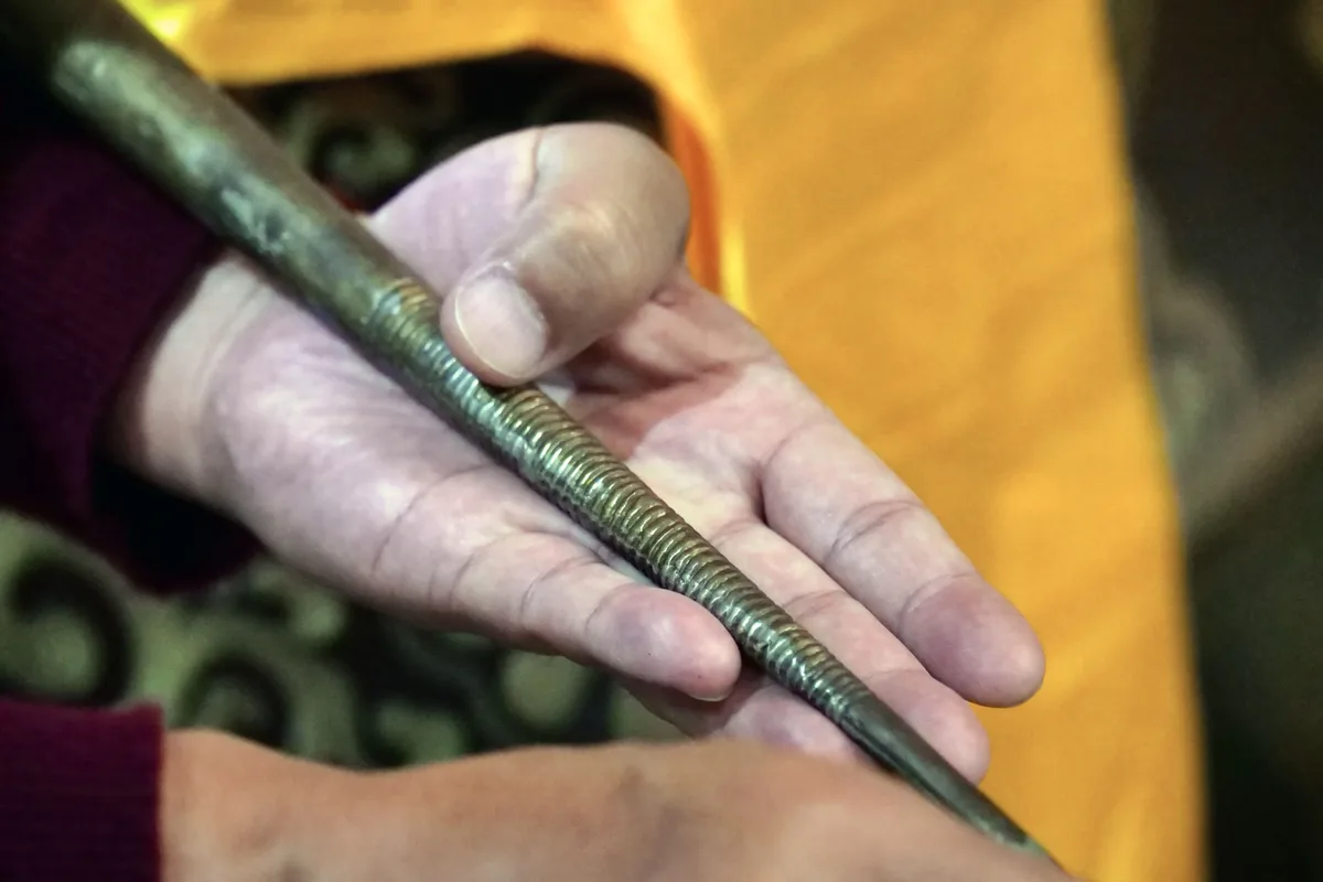 Man sieht eine Hand, die ein Metallrohr hält.