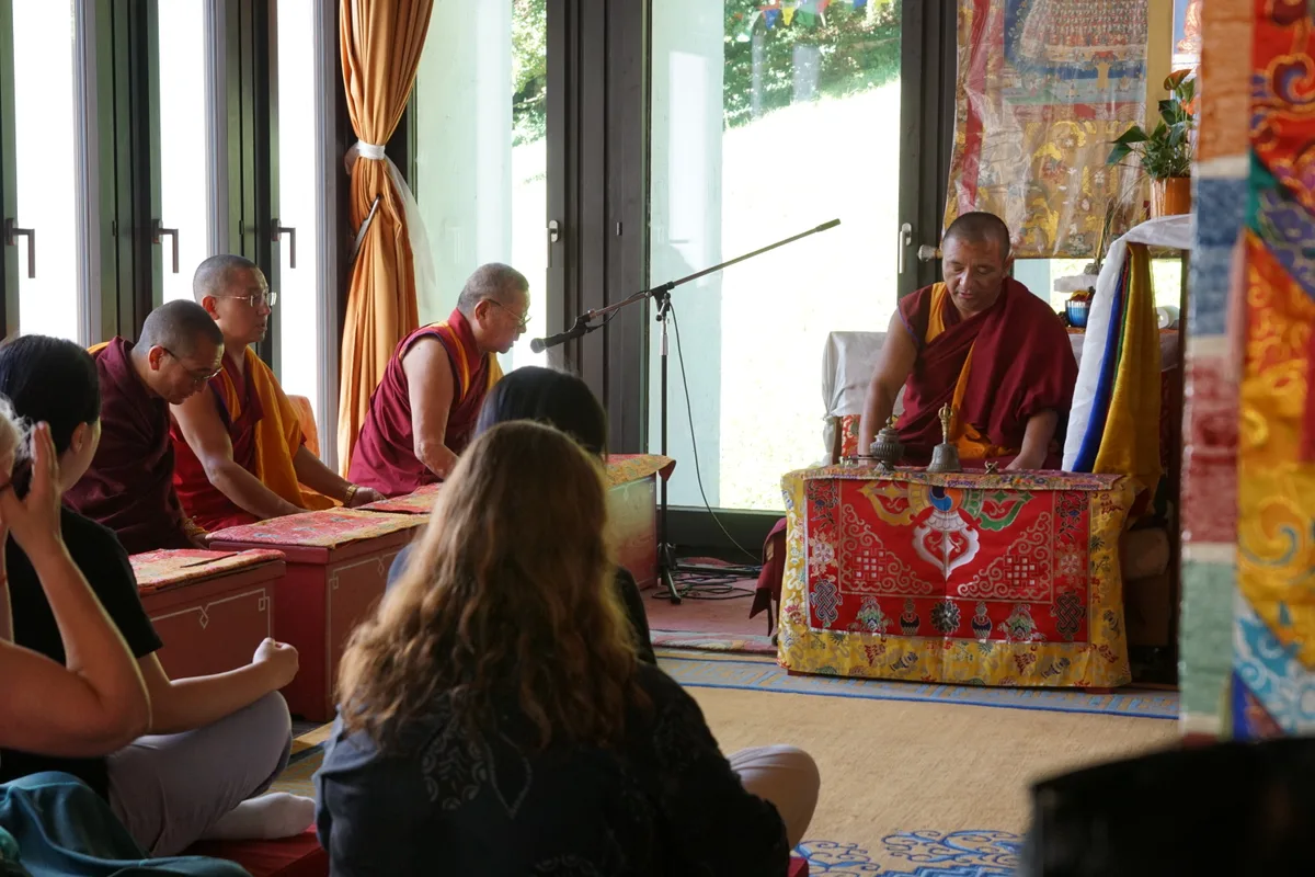 Man sieht buddhistische Mönche beim Meditieren im Gebetsraum.
