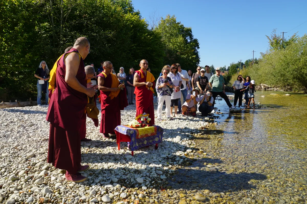 Man sieht die buddhistischen Mönche und die Besucher an der Töss.
