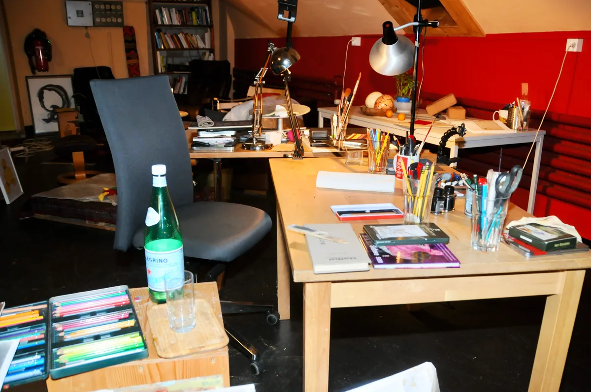 Man sieht einen Arbeitsplatz mit sehr vielen Utensilien zum Zeichnen.